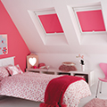 Pink perfect fit blinds in a attic bedroom setting.