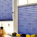 Blue pleated blinds with a falling flower motif pattern in a kitchen setting.