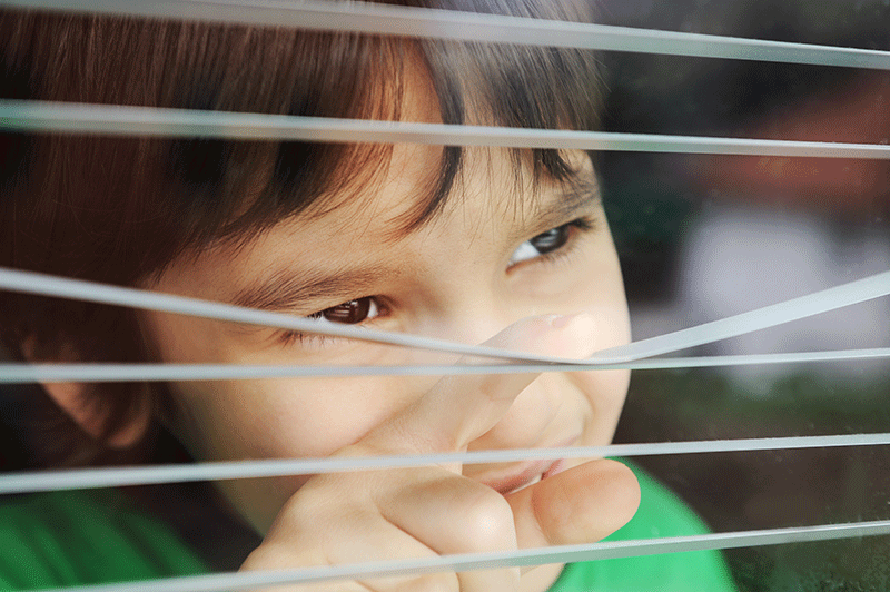 child looking through blinds